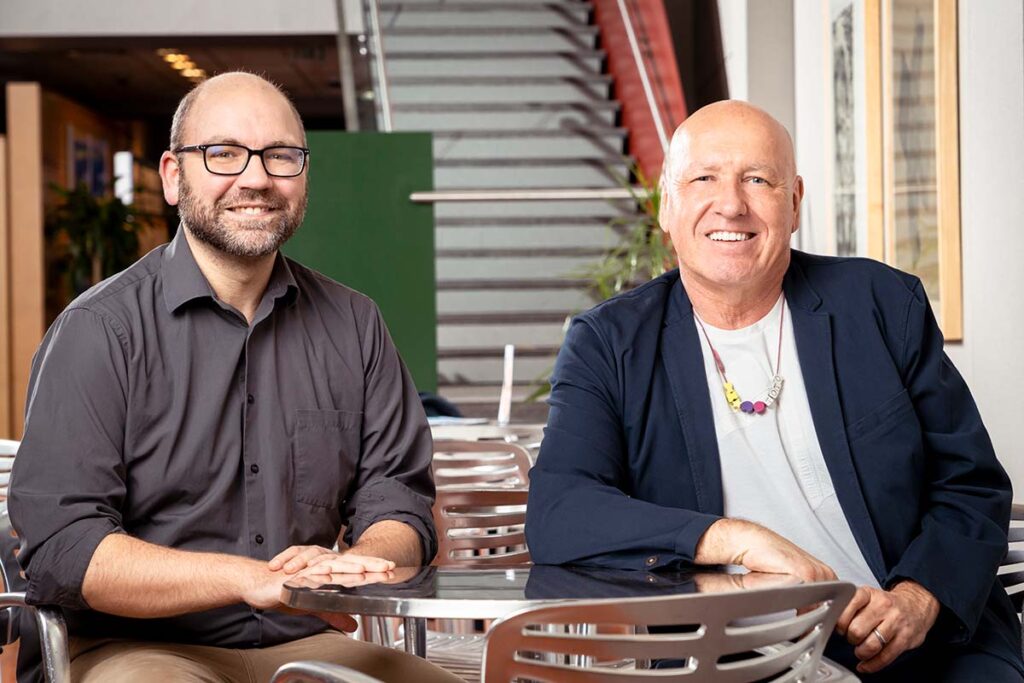 APL PI Erik Johnson, Ph.D., and WSE PI Thomas Hartung, Ph.D., M.D., are seated beside each other at a metal table.